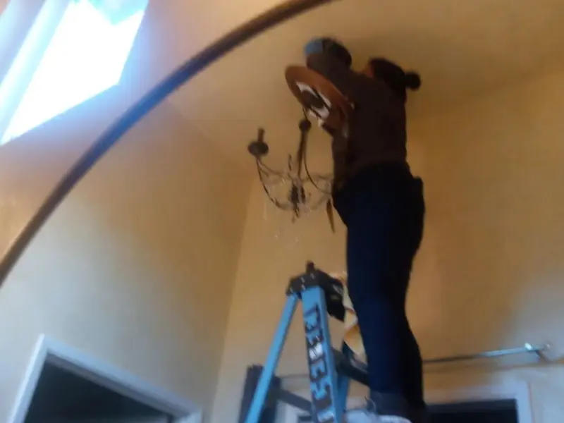 Electrician installing a chandelier in a Adelanto residence